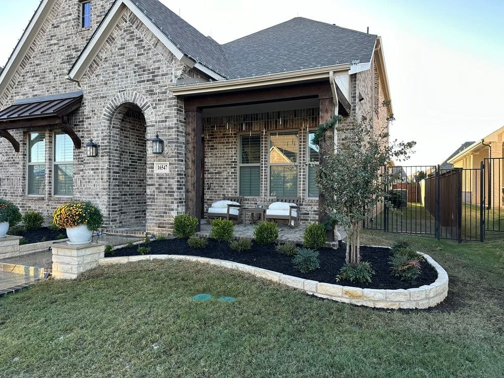 Brick home exterior with landscaped front yard, porch seating, and decorative flower pots.