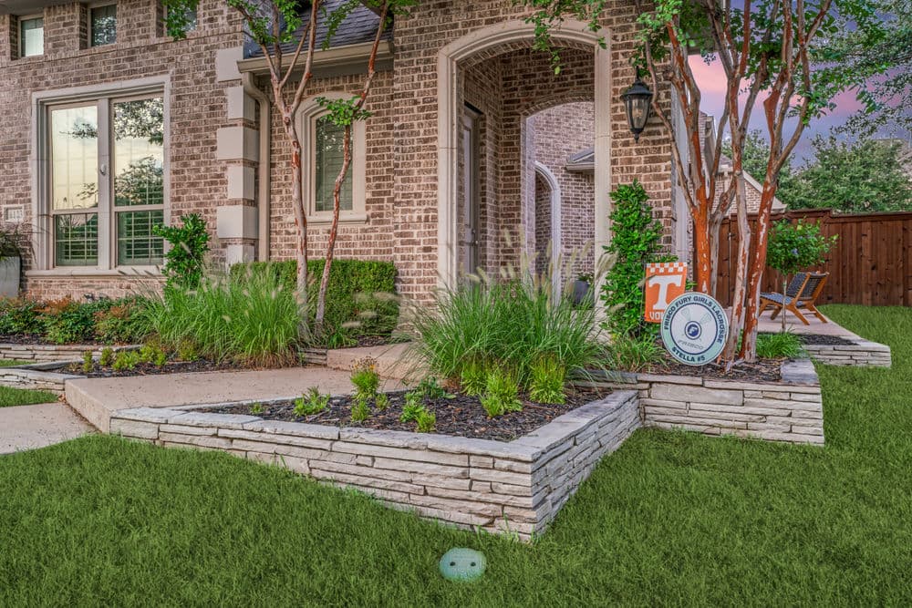 Beautiful landscaped garden with stone borders, vibrant greenery, and a welcoming entrance.